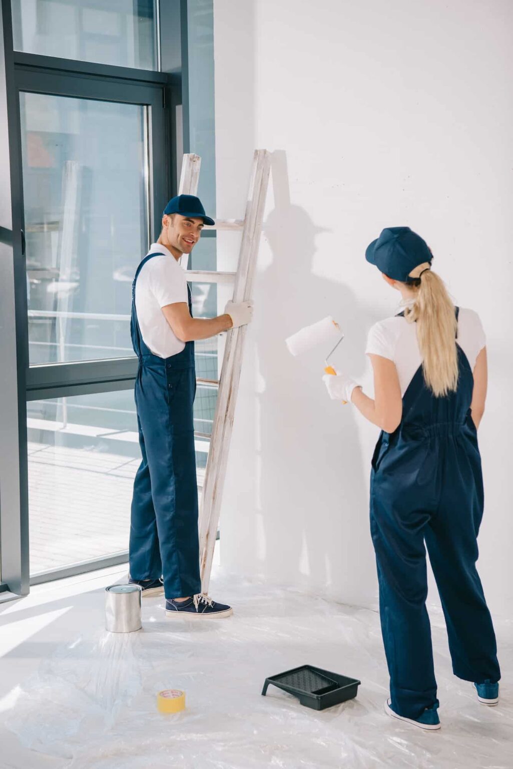 "Professional painters at work, meticulously painting the interior walls of a room during a home renovation.