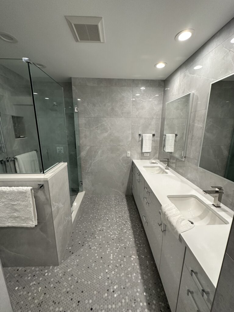 A spacious bathroom with marble countertops and a glass-enclosed shower