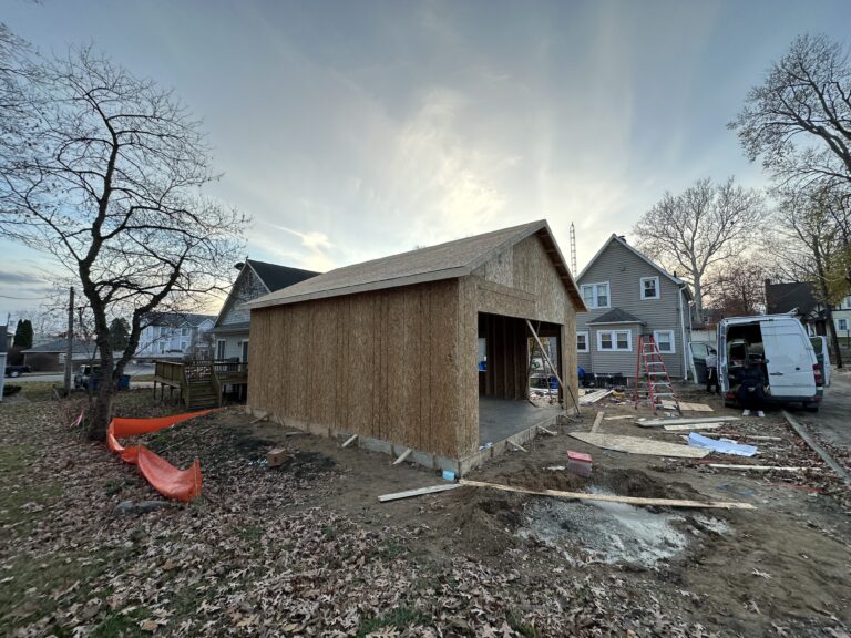 A beautifully finished house featuring expertly crafted wooden walls and a sloping tiled roof, set against a clear sky.